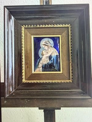 un tableau représentant une femme tenant un enfant, posé sur un chevalet