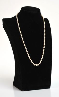 un collier de perles blanches sur un mannequin noir, devant un fond blanc