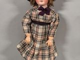 an image of a doll wearing a dress and a hat