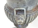 a large metal urn with a lion head on it