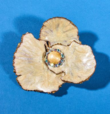 a close up of a flower brooch on a blue surface
