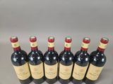 six bottles of red wine lined up in a row on a table
