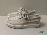 des chaussures bateau blanches avec des lacets blancs, posées sur une surface blanche