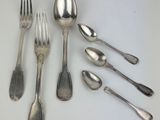 six silver spoons and a fork on a white surface