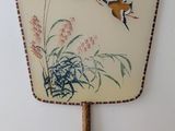 a fan with a painting on it hanging on the wall