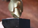 a gold statue of a bird on a black base