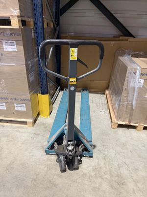 une photo d'un chariot élévateur dans un entrepôt, avec des cartons en arrière-plan
