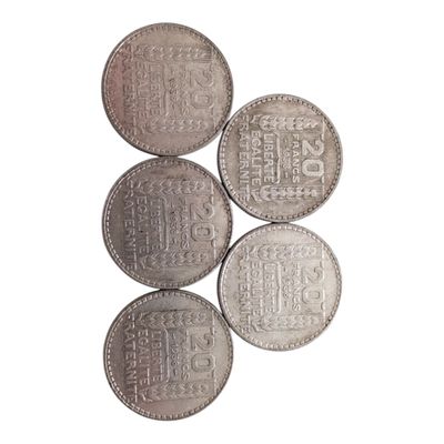 cinq pièces d'argent empilées les unes sur les autres sur une surface blanche