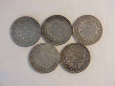 six different coins are arranged in a row on a white surface