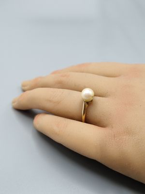 Une bague en perle plaquée or à la main d'une femme