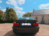 a black car parked in front of a house on a dirt lot