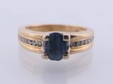 a close up of a ring with a sapphire stone and diamonds