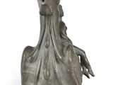a silver vase with a bird on it on a white surface
