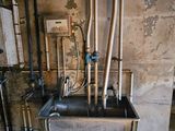 a sink in the middle of a dirty room with pipes