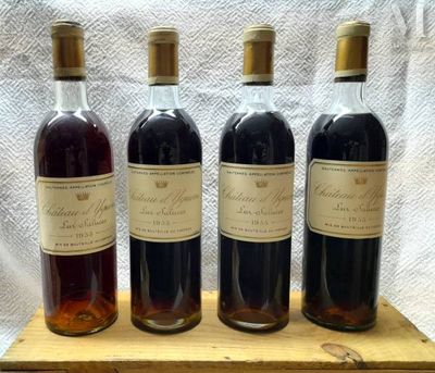 quatre bouteilles de vin sont alignées sur un plateau en bois