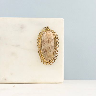 une plaque en marbre blanc sur laquelle est apposée une broche ovale dorée
