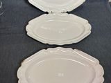 trois assiettes vides sur une table, avec un verre de vin