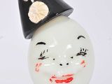 un vase blanc surmonté d'un chapeau noir