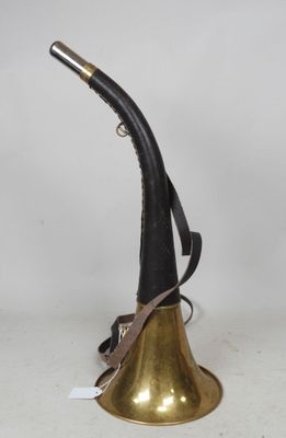 une cloche en laiton avec une poignée noire posée sur une table blanche