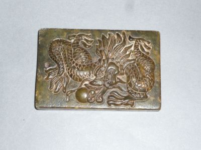 une image représentant une boucle de ceinture en métal ornée d'un dragon et d'un poisson