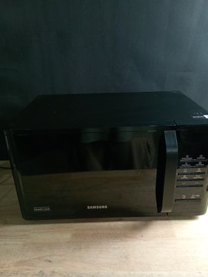un four à micro-ondes noir posé sur une table en bois