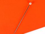 a needle is placed on top of an orange piece of paper