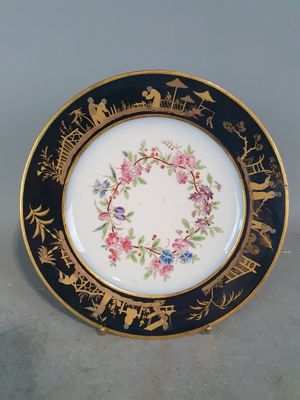 une image représentant une assiette noire et dorée ornée de fleurs