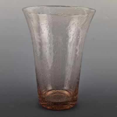 a clear glass vase with a brown base on a table