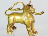 une statue en or représentant un lion avec une pipe dans la gueule