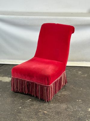 une chaise rouge ornée de franges, posée par terre