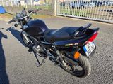 a motorcycle that is parked on the street in front of a fence