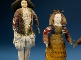 three figurines of men and women dressed in period clothing