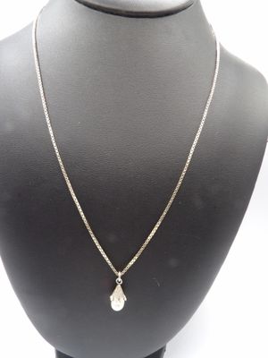 a silver necklace with a white pearl pendant on a mannequin