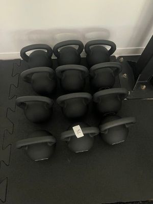 de nombreux kettlebells noirs posés sur un tapis noir