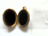 une image représentant deux pierres noires à l'intérieur d'un pendentif en or