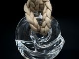 un vase en verre contenant une corde, posé sur une surface noire