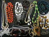 a lot of beads and necklaces that are on a table