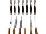six knives are lined up in a row on a white surface