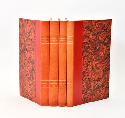 trois livres rouges sont empilés sur une surface blanche