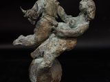 bronze statue of a man sitting on top of a rock