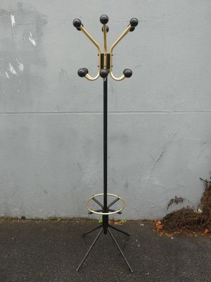 a black and gold coat stand with three coats on it
