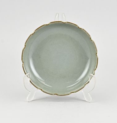 une image représentant une assiette verte posée sur un support, sur une surface blanche