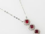 a close up of a necklace with three red stones on it