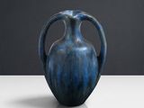 un vase bleu posé sur une table, sur fond noir