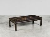 une table basse noire et dorée posée sur un sol en béton