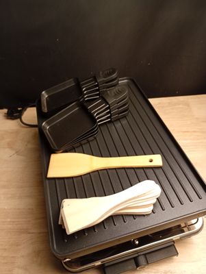 une image représentant un barbecue sur lequel sont posés une spatule et des ustensiles