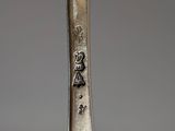 an old silver spoon with a bird on it sitting on top of a table