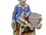 a figurine of a boy sitting on a chair with a basket