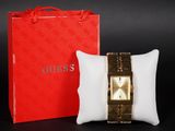 un oreiller blanc posé à côté d'une boîte rouge et d'une montre en or