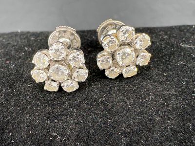 a pair of diamond earrings on a black surface